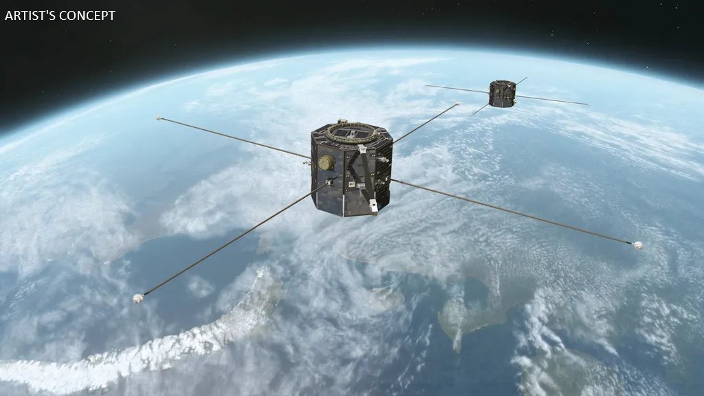 "Artist's concept of two dark-colored satellites, one in the foreground and one in the background, orbiting above a blue and white Earth. Each satellite has long, thin antennae extending outwards, with small spheres at their ends. Clouds are visible on the Earth's surface."